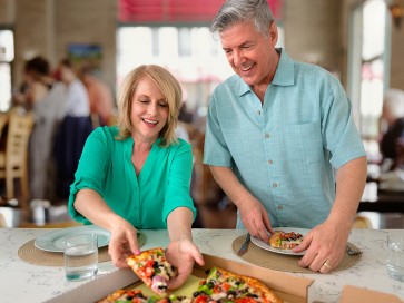 Article image: Healthy and happy middle aged couple eating pizza - CCM Health Reflux and Foregut Surgery